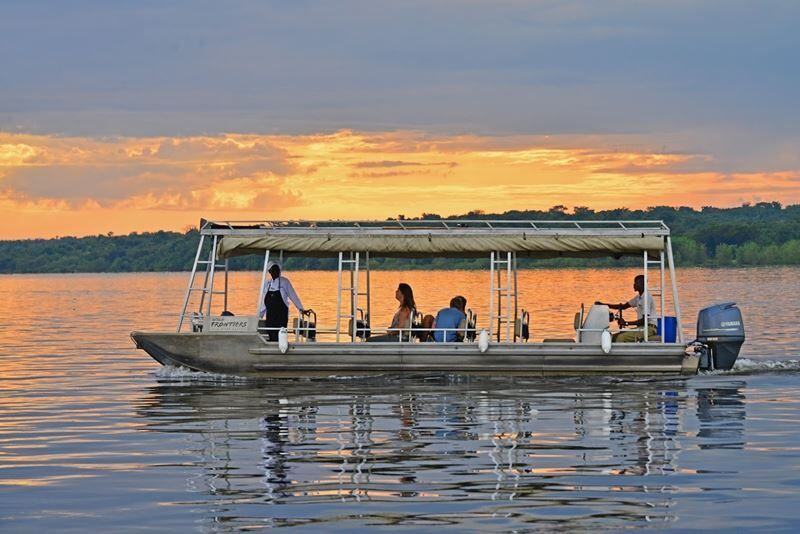Safari boat with guests on calm water at sunset